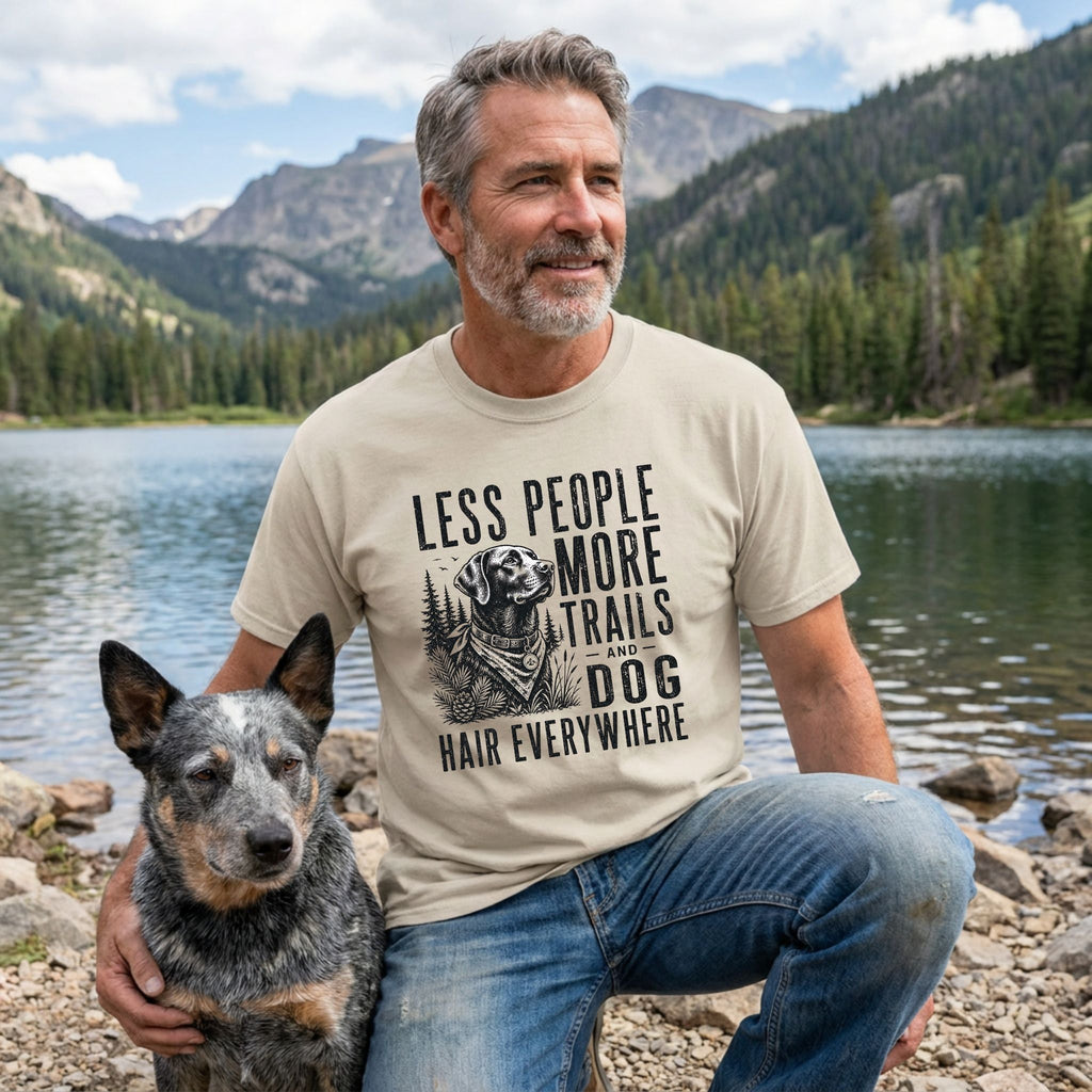 Man wearing a beige crewneck t-shirt with a black graphic of a dog and the text Less People More Trails and Dog Hair Everywhere.