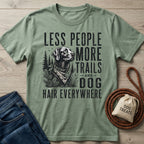 Sage green cotton t-shirt featuring a black graphic of a dog in the woods with the text Less People More Trails and Dog Hair.