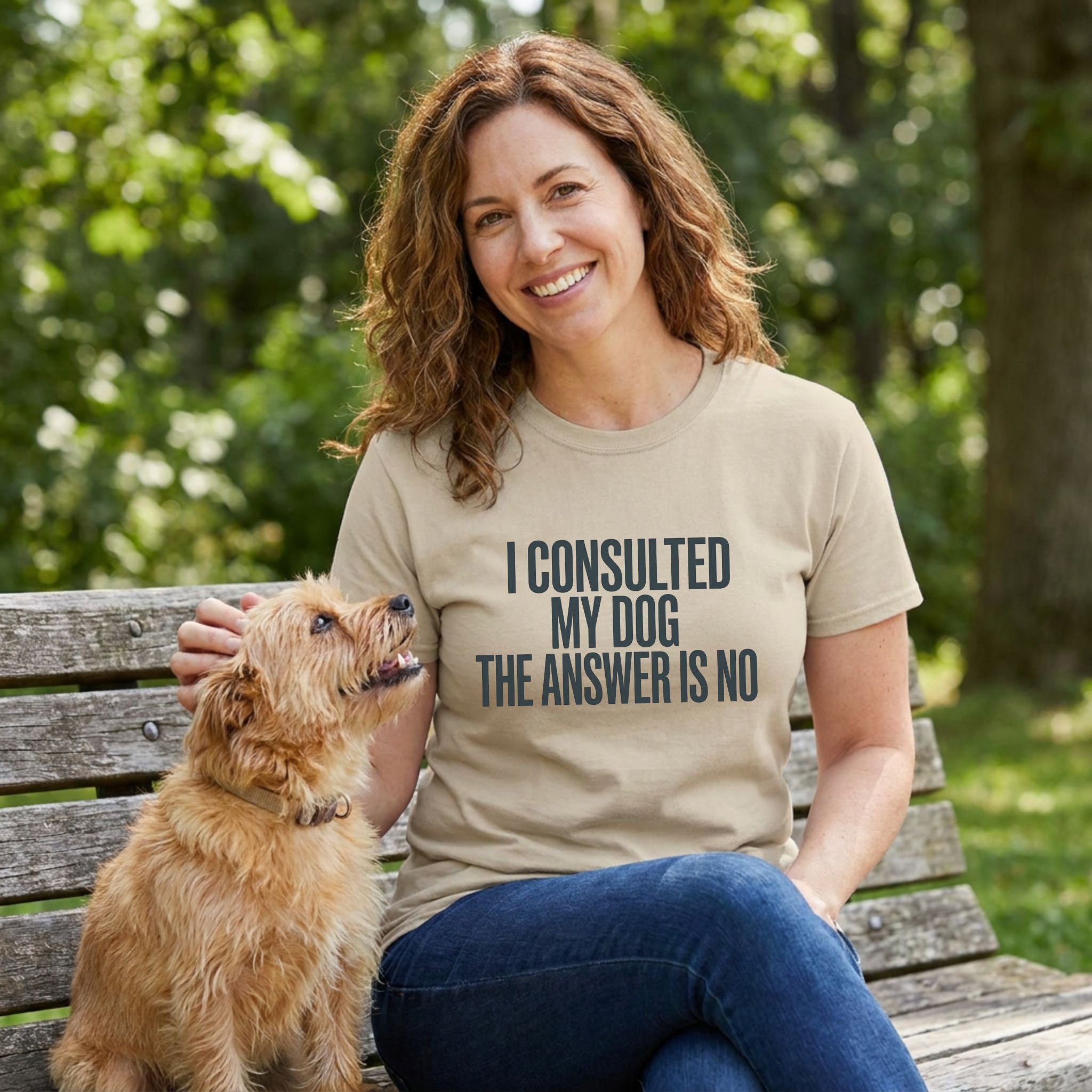 Woman in a tan Gildan Softstyle® "My Dog Said No" t-shirt petting a small brown dog on a park bench.