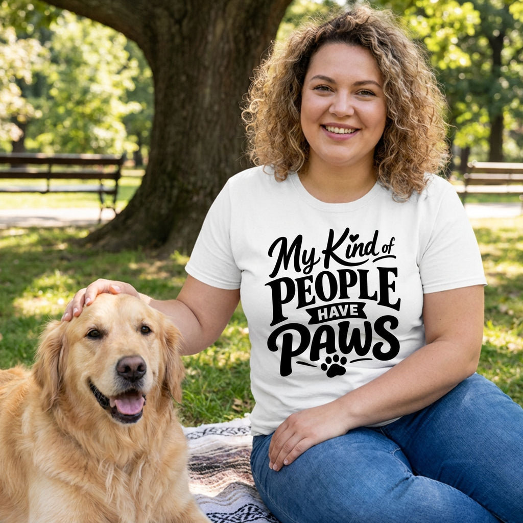 Woman wearing a white crew neck t-shirt with My Kind of People Have Paws text, petting a golden retriever in a park.