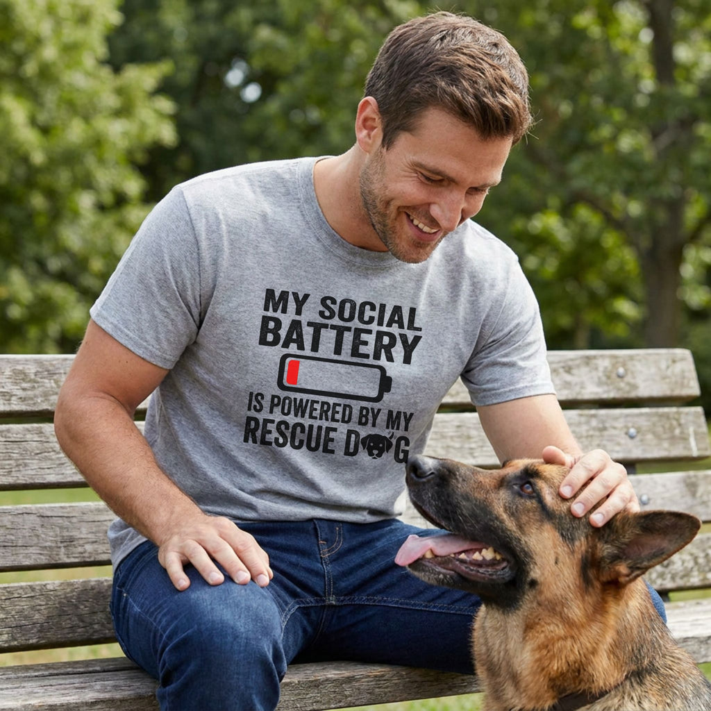 Man in a grey "My Social Battery Is Powered By My Rescue Dog" t-shirt petting a German Shepherd.