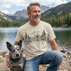 Beige crewneck t-shirt featuring a mountain and dog reflection graphic, worn by a man with a dog by a lake.