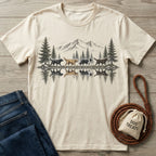 Cream-colored crew neck t-shirt featuring a detailed mountain and dog reflection graphic, laid on a wooden surface.