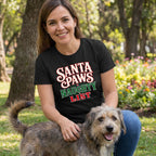 Woman wearing a black T-shirt with Santa Paws Naughty List text in red, white, and green, petting a scruffy dog outdoors.