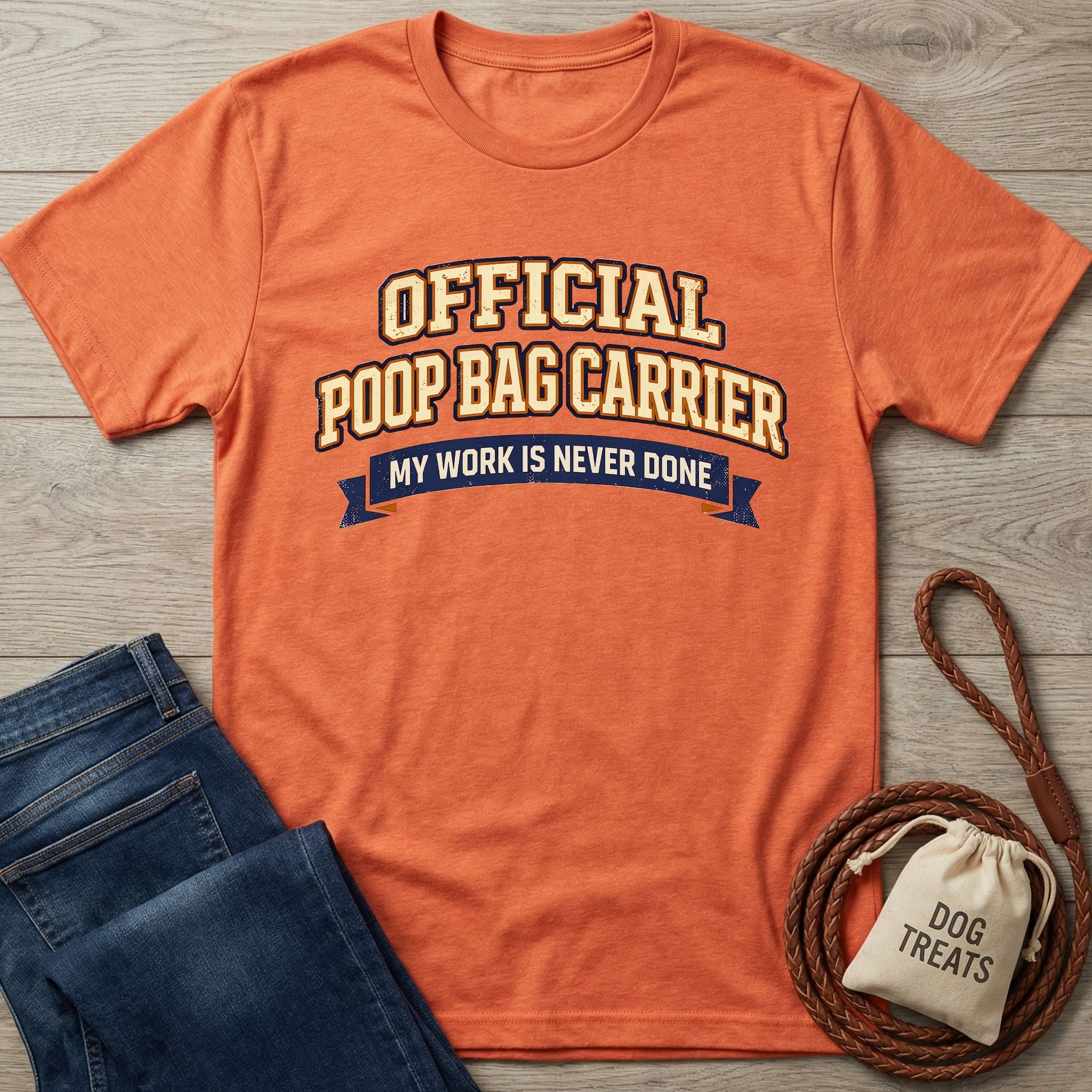 Orange Gildan Softstyle® t-shirt with "Official Poop Bag Carrier" text, next to jeans and dog treats.