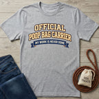 Light grey Gildan Softstyle® t-shirt with "OFFICIAL POOP BAG CARRIER" text, next to jeans and dog treats.