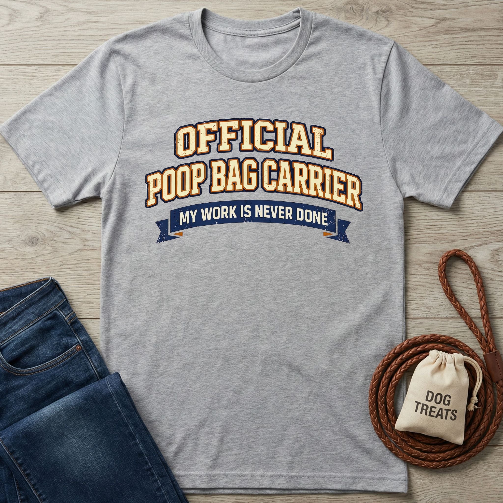 Light grey Gildan Softstyle® t-shirt with "OFFICIAL POOP BAG CARRIER" text, next to jeans and dog treats.