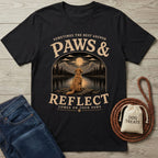 Black cotton t-shirt featuring a Golden Retriever gazing at a moonlit mountain lake with the text Paws & Reflect.