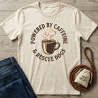Cream Gildan Softstyle t-shirt with "Powered By Caffeine & Rescue Dogs" graphic, next to jeans and dog treats.