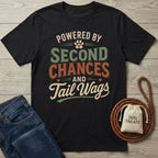 Black Gildan Softstyle® t-shirt with "Powered By Second Chances and Tail Wags" design, dog treats, and jeans.