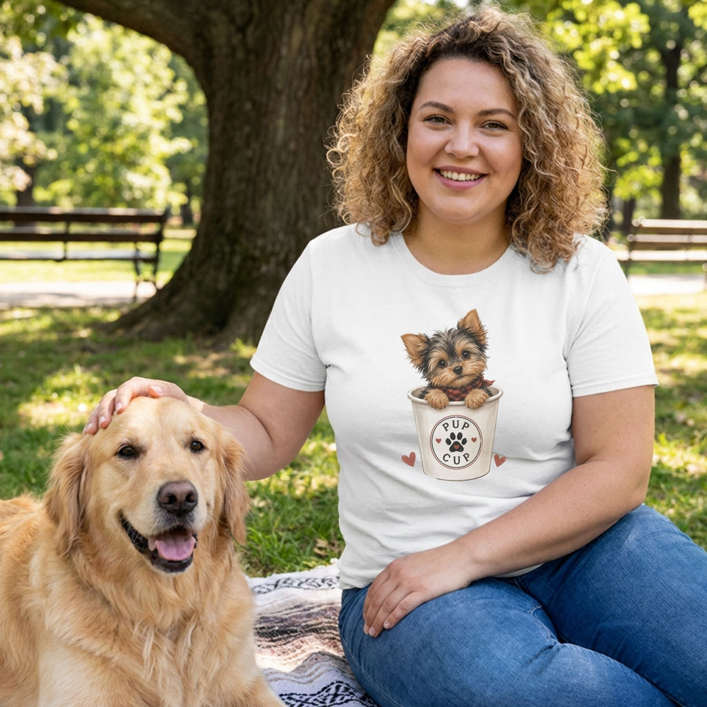 Woman wearing a white crewneck t-shirt featuring a cute illustration of a puppy in a pup cup, sitting outdoors with a dog.