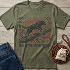 Olive green t-shirt featuring a woodblock-style print of a dog leaping over a log with the text Trail Tested, Rescue Approved.