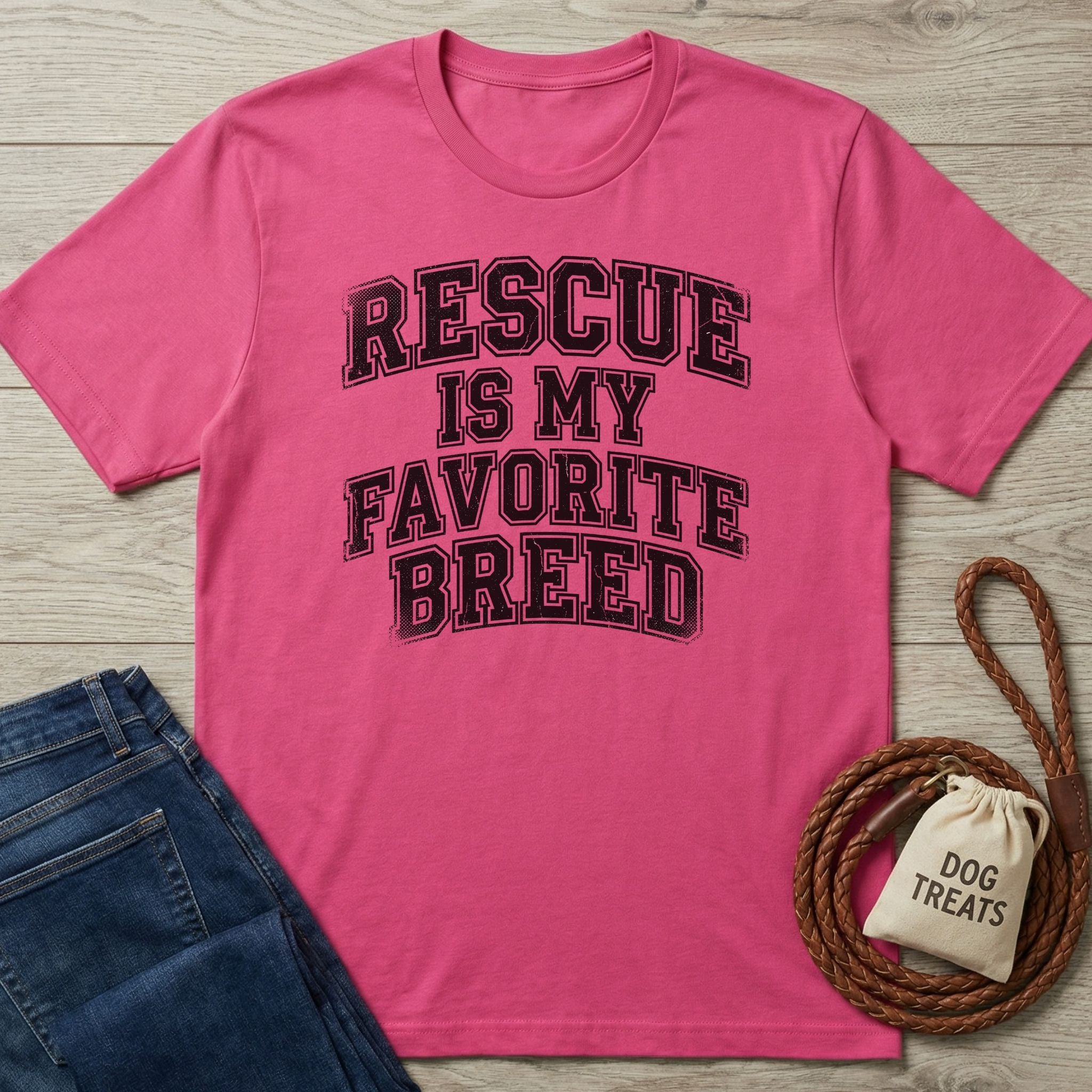 Pink Gildan Softstyle t-shirt with "Rescue Is My Favorite Breed" text, next to jeans and dog treats.