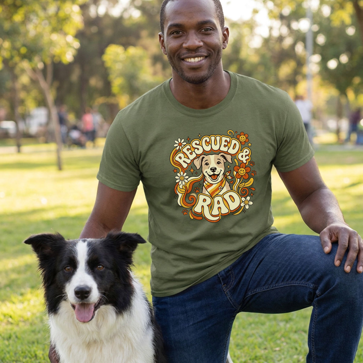 Man in olive green "Rescued & Rad" t-shirt with a smiling dog design, kneeling beside a black and white border collie.