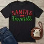 Black cotton T-shirt featuring Santa's Favorite in red and green text with a dog bone icon, styled with jeans and a treat bag.