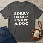 Charcoal grey Gildan Softstyle t-shirt with "Sorry I'm Late I Saw A Dog" text, next to blue jeans and dog treats.