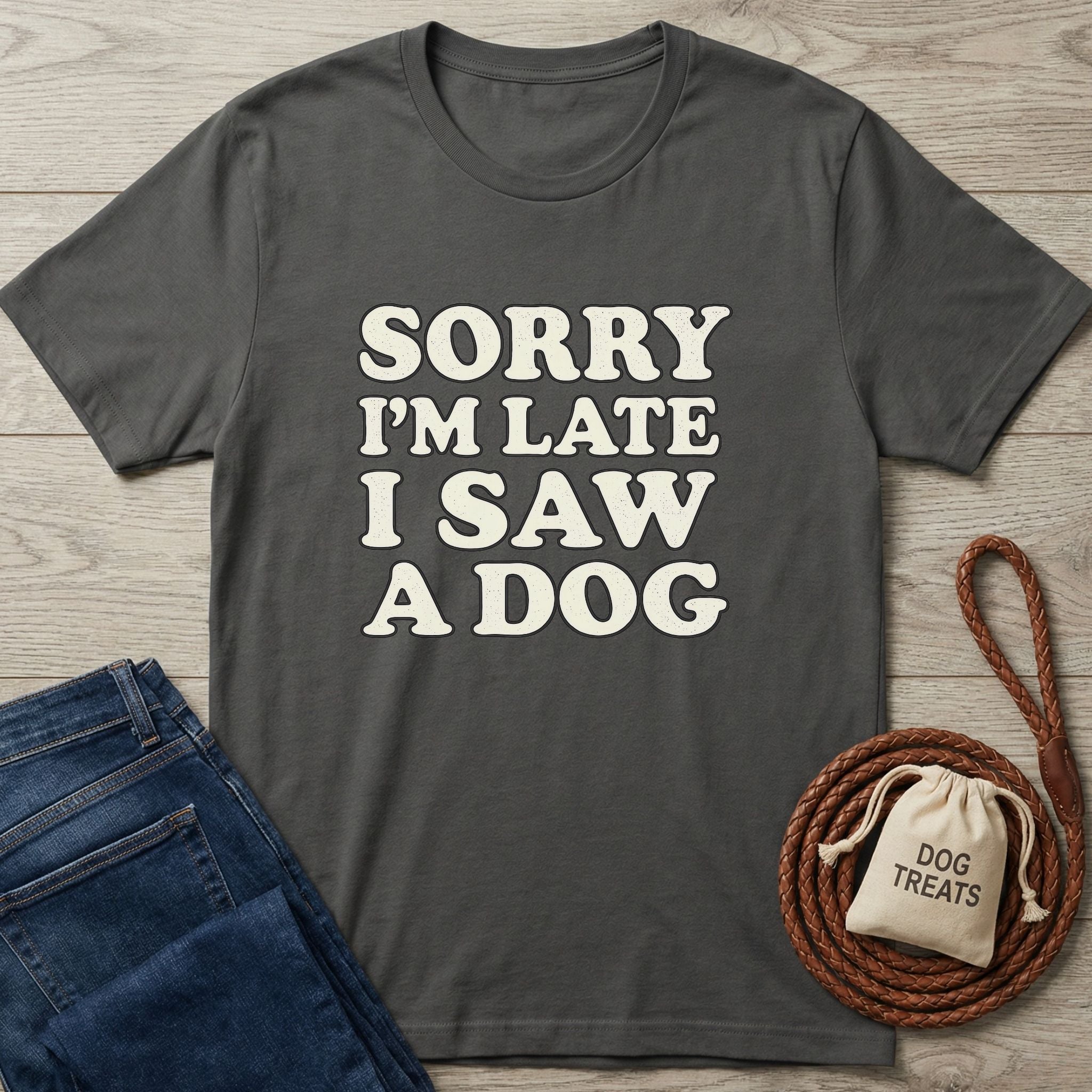 Charcoal grey Gildan Softstyle t-shirt with "Sorry I'm Late I Saw A Dog" text, next to blue jeans and dog treats.