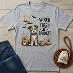 Grey crewneck t-shirt featuring a wide-eyed dog, pumpkins, and the text Wired, Tired, Spooked for Halloween.