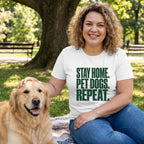 Woman in white "Stay Home. Pet Dogs. Repeat." t-shirt petting a golden retriever in a park.