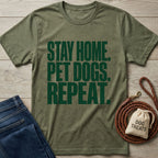 Olive green Gildan Softstyle® t-shirt with "STAY HOME. PET DOGS. REPEAT." text, next to jeans and dog accessories.