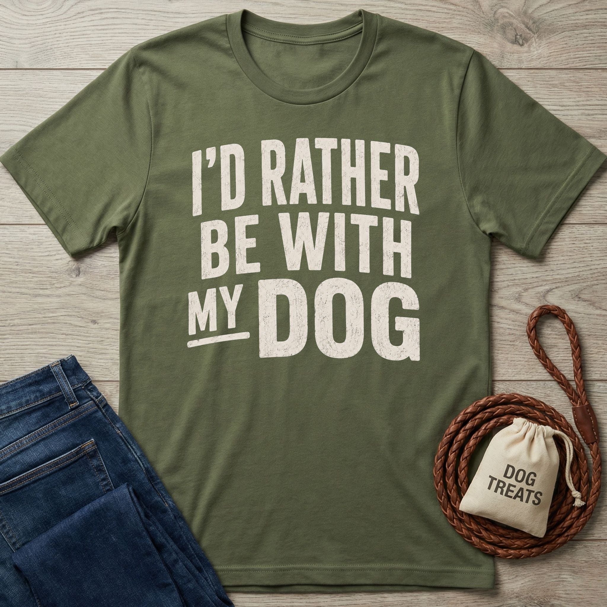 Olive green crewneck t-shirt with distressed white text reading I'D RATHER BE WITH MY DOG, styled with jeans and a treat bag.