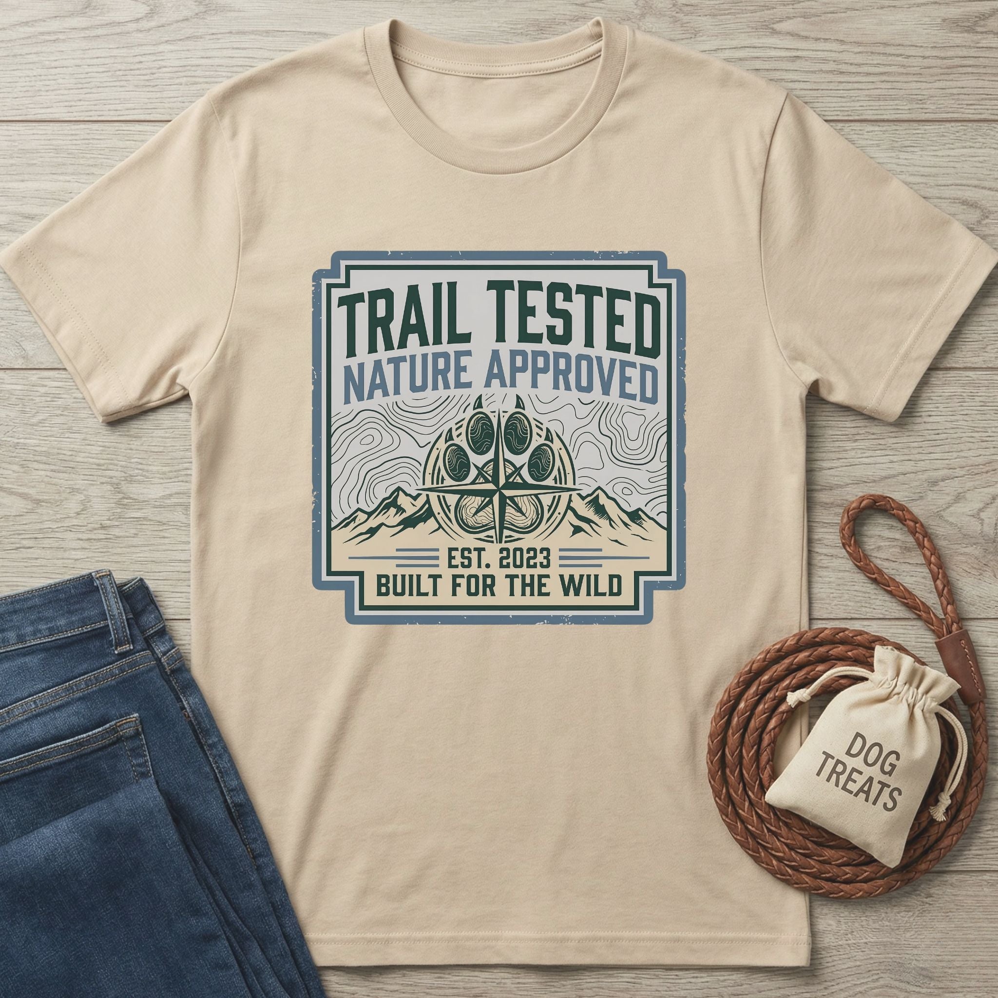 Beige "Trail Tested Nature Approved" graphic tee with jeans, dog treats, and braided leash.