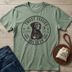Sage green "Trust Issues Society" t-shirt with a black dog graphic, paired with jeans and a dog treat bag.