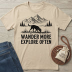 Beige cotton t-shirt featuring a black graphic of a dog exploring mountains with the text Wander More Explore Often.
