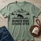 Sage green crewneck t-shirt featuring a black graphic of a dog hiking in the mountains with the text Wander More Explore Often.