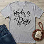 Grey crewneck t-shirt with black cursive text reading Weekends Are For The Dogs, laid flat with jeans and a dog leash.