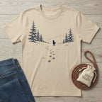 Beige cotton t-shirt featuring a black mountain, pine forest, and dog paw print graphic on a wooden background.