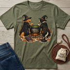 Olive green crewneck t-shirt featuring two dogs in witch hats stirring a bubbling cauldron with the text Witches Brew.