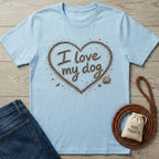 Light blue crewneck t-shirt featuring an I love my dog heart design made of sand and seashells on a wooden background.