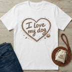 White crewneck t-shirt featuring an I love my dog heart design written in sand with seashells on a wooden background.